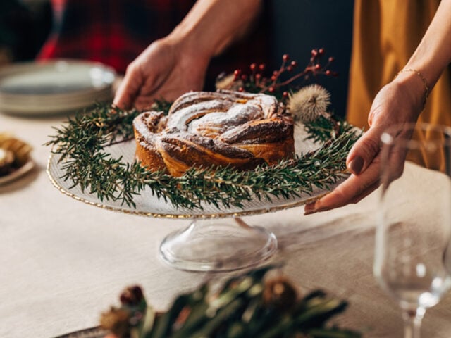 Holiday foods. Woman placing a healthy holiday cake onto the table for Christmas.