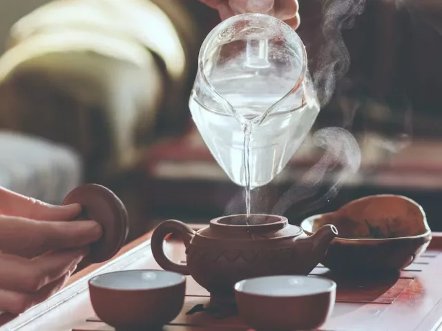 Woman pouring hot water to brew tea, one of the approved drinks on a bland diet to help prevent heartburn