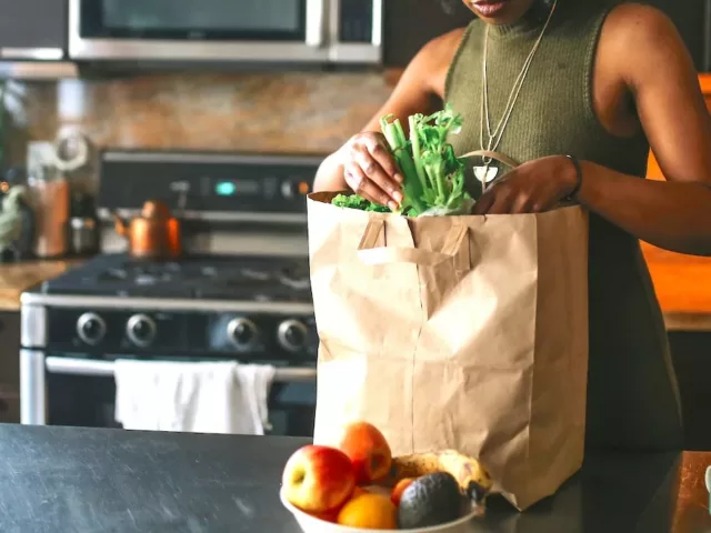 Woman unpacking her grocery bag of the fruits and vegetables